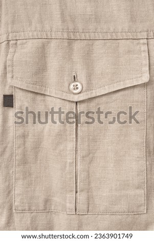 Beige linen fabric shirt flap patch pocket closeup as a background Royalty-Free Stock Photo #2363901749