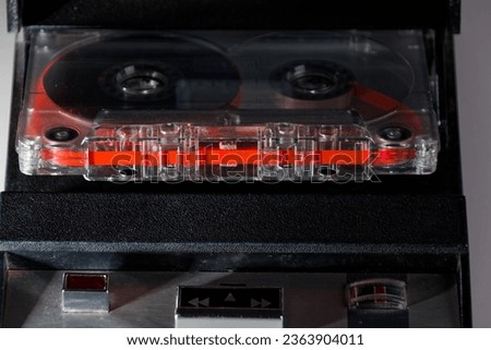 vintage analog audio cassette with transparent case and visible tape from the 80s with vintage cassette recorder