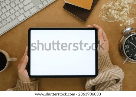 Woman hand holds digital tablet mockup with blank screen, education and application concept template, bright brow background, top view and copy space photo.
