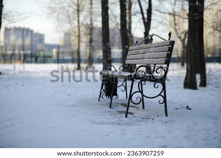 park bench on a winter alley at snowfall. bench with snow after snowstorm or in snow calamity in europe, winter night  photography in city