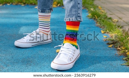 Odd Socks Day. a child in sneakers and mismatched socks stands on the playground. close-up of feet in colored socks. Royalty-Free Stock Photo #2363916279
