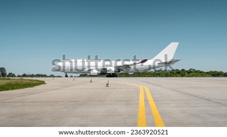 Huge white passenger aircraft accelerating for take-off along the runway, hot exhaust coming out of the engine and distorts the visibility. Side view of two-storey jumbo jet on a ground on a sunny day Royalty-Free Stock Photo #2363920521