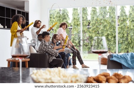 Diverse friends or people wearing casual clothes, Paper shooting for party celebration, sitting in living room at cozy home, happily playing guitar, screaming, singing. Birthday, New Year Concept