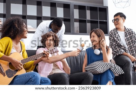 Group of diverse friends or people wearing casual clothes, relax smiling with happiness, party celebration, sitting in living room at cozy home, playing guitar and singing. Birthday, New Year Concept