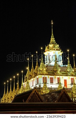 The photo beautifully captures a temple at night, the golden spires of which pierce the dark sky.