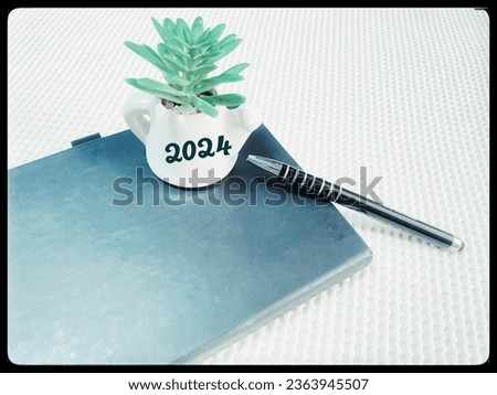 2024 content notebook Black placed on a white table, vase, year 2024