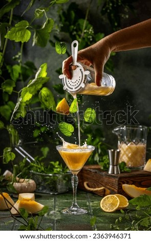 Woman preparing melon margarita cocktail with mint in glass on dark green ceramic tile background, close up. Summer autumn drinks and alcoholic cocktails. Alcoholic cocktail or detox drink