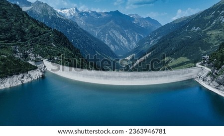 picture presents a breathtaking scenery of towering mountains, shimmering waters, and a colossal dam standing proudly amidst the natural landscape. The majestic mountains create a stunning backdrop