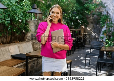 Portrait of an attractive woman who is talking on the phone looking for her colleagues in a cafe