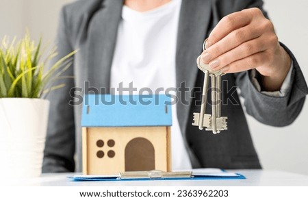 Realtor or real estate agent giving keys to buyer after singing contract. House model on the table. Home loan, mortgage, investment, rent, real estate, property concept. Selective focus