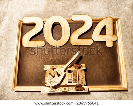 Wooden numbers and symbols of new year 2024 with frame and tank. Military tense relations in the world. War between Russia and Ukraine. Defense and offensive concept, dangers of military technology