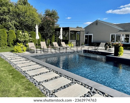 Stunning luxury backyard view of pool, chaise lounges, garden, pergola with hot tub.  Modern and sleek, it has an effortless boho inspired, resort like feel. Inspired by Tulum, Mexico's eco-chic feel. Royalty-Free Stock Photo #2363974763