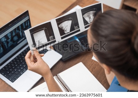 Diagnostic Ultrasound: In her blue scrubs, the doctor reviews ultrasound images and maintains meticulous notes on her laptop for comprehensive patient records.
