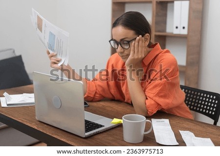 Bored woman pays domestic bills online using computer app bank customer holds papers making credit insurance payment at home on laptop at wooden table in accommodation