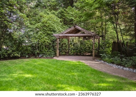 Pavilion or pergola in the garden surrounded by greenery and a lawn. Wooden gazebo for relaxing in a summer park. Walkway Path With Green Trees. Pathway in a Summer Park with trees and green grass Royalty-Free Stock Photo #2363976327
