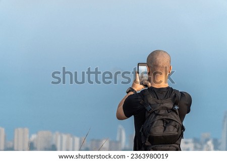 Young hiker with backpack recording a video with the smartphone to the landscape Royalty-Free Stock Photo #2363980019