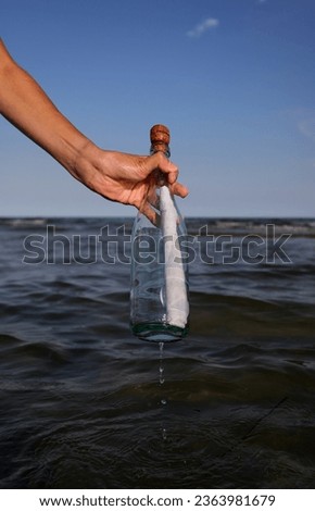 boy takes a bottle with a secret message on the sea in summer