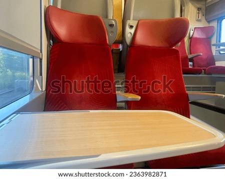 Passenger train wagon in transit with empty red seats. With no people on board. Public transportation for short long distances. Interior of a high-speed train in Europe.