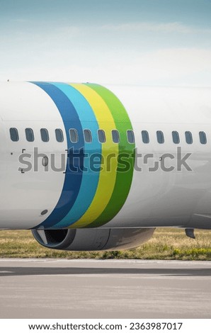 Fuselage of passenger aircraft. Vertical image of fuselage section with colored rings. Close-up view of airplane parked on apron.