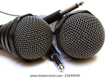 Two black wired karaoke microphones with gray metal grill on isolated background.