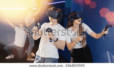 Young guy and girl in vr headset stand shoulder to shoulder interacting with digital interface.Students is testing equipment for training, games, entertainment in virtual reality