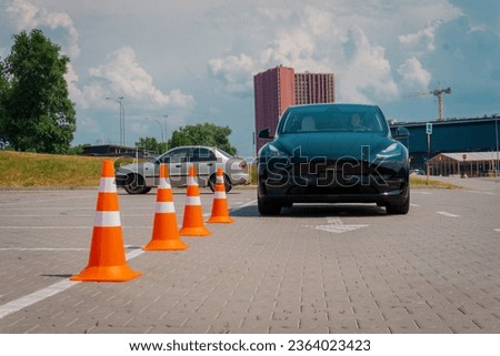 Traffic cones near car outdoors. Driving school exam. Young woman driver driving test Driving test, driver courses, exam concept Royalty-Free Stock Photo #2364023423