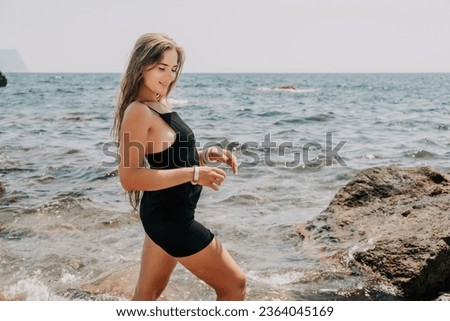 Woman summer travel sea. Happy tourist in hat enjoy taking picture outdoors for memories. Woman traveler posing on the beach at sea surrounded by volcanic mountains, sharing travel adventure journey