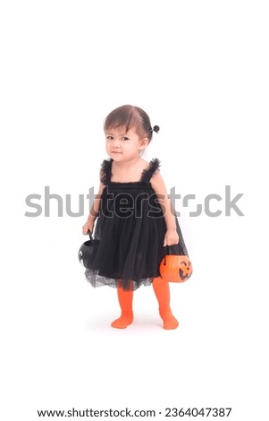 Studio shot of a baby gril kid holding a Jack O'lantern pumpkin on a white background. The concept of Halloween festival trick or treak.