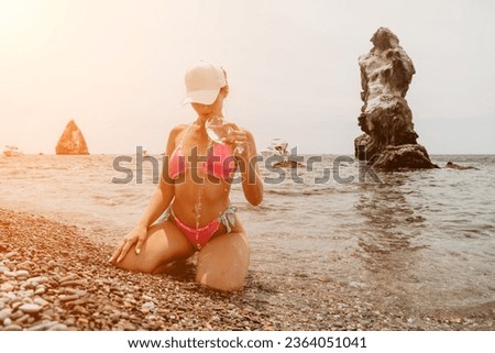 Woman travel sea. Happy tourist in pink bikini enjoy taking picture outdoors for memories. Woman traveler takes photo by sea. Volcanic mountains surround her on beach for adventurous journey.