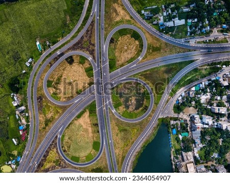 A top view of Dhaka - Bhanga Expressway. beautiful Bangladeshi road.  Aerial top view at highway intersection or road junction with circle movement, cars and trucks traffic. Royalty-Free Stock Photo #2364054907