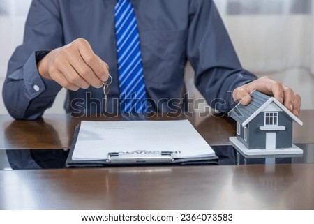 Real estate agents hand holding home model, explains the business contract for signing a business contract, renting, buying, mortgage, loan or home insurance.