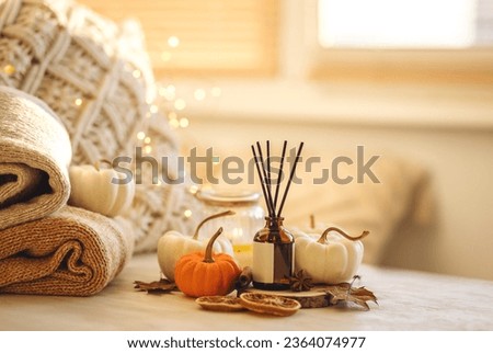 Autumn mood, cozy fall home atmosphere. Aroma diffuser, pumpkins, knitted warm sweaters, burning candles, dry leaves on wooden table. Concept of house decor, apartment seasonal fragrance. Thanksgiving Royalty-Free Stock Photo #2364074977