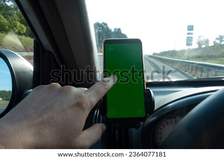 Modern smart phone with isolated green screen for mockup. The driver uses the phone on car road.