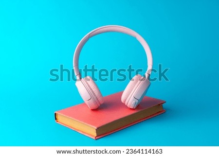 Pink headphones on a book on blue background