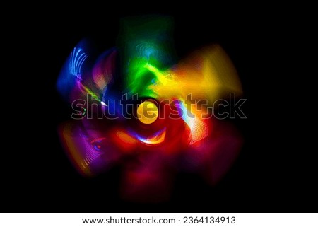 A front view of a regular toy pinwheel windmills with six differently psychedelic colored vanes rotating on a stick on a black screen background, slow shutter speed motion blur Royalty-Free Stock Photo #2364134913