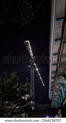 Construction Crane With Red Lights And Blue Sky At Night
