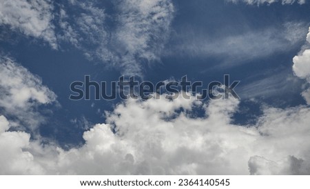 A bright sunny day with blue sky and white patches of snowy clouds sailing on it.