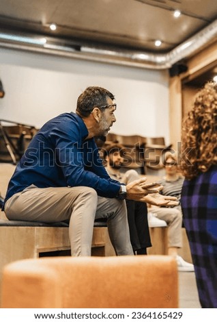 Senior business employee discussing with his colleagues in meeting. Project team leader helping his teammates with the project in meeting at modern amphitheater. Royalty-Free Stock Photo #2364165429