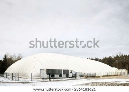 Inflatable air dome stadium. Inflated Football soccer air dome. Modern architecture example pneumatic stadium dome with heat generators, hot air blower and air conditioning system near winter forest. Royalty-Free Stock Photo #2364181621