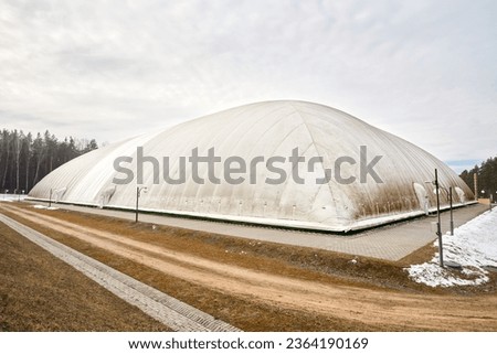 Inflatable air dome stadium. Inflated Football soccer air dome. Modern architecture example pneumatic stadium dome with heat generators, hot air blower and air conditioning system near winter forest. Royalty-Free Stock Photo #2364190169