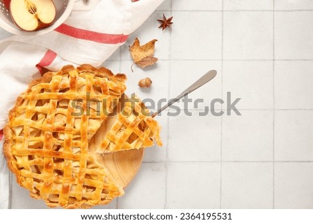 Wooden board with delicious apple pie on white tile background