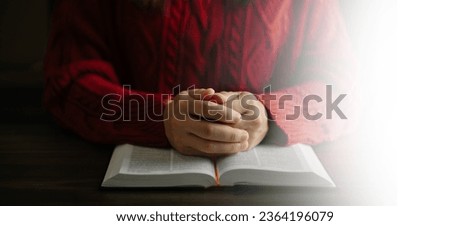 Hands together in prayer to God along with the bible In the Christian concept and religion, woman pray in the Bible on the wooden table in sun light
