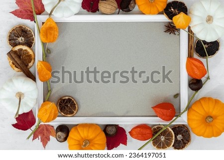 Mock up flat lay template white portrait frame with fall branches and pumpkin decor on wooden background. Autumn concept with copy space for text