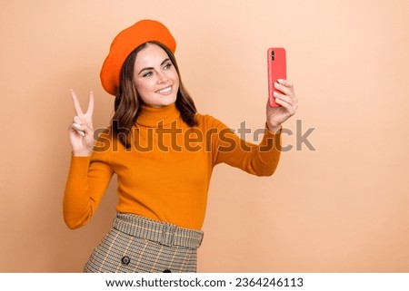 Photo of charming blogger wear autumn orange outfit make self picture look camera recording video v-sign isolated on beige color background
