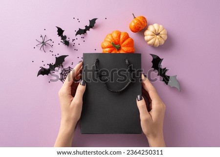 Halloween-inspired shopping event: First person top view of female hands holding black shopping bag, with blast of pumpkins, spider, cobweb, and bats on lilac backdrop. Ideal for promotions