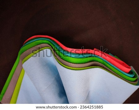 Bandung, Sept 20, 2023 : Background from colorful curves lines side bunch of nylon fabric on brownies black fabric at home.