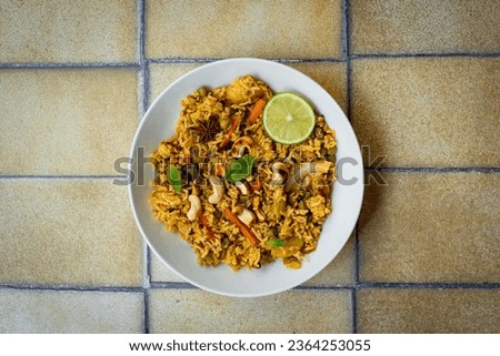 Biryani in plate with lime on yellow background. Flat lay photography.