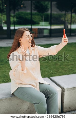 Happy 30s Women taking selfie. Young beautiful girl say Hi. Attractive Woman using smart phone app over street background, online communication concept.