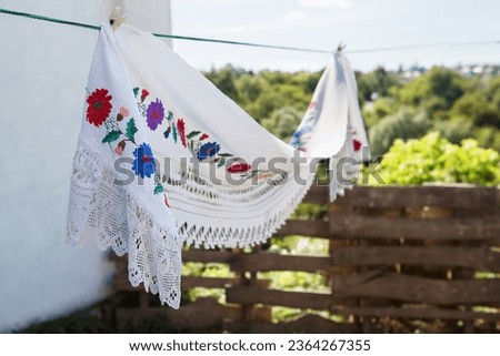 Traditional Ukrainian embroidered towel hangs on a rope in the yard. Vyshyvanka. Royalty-Free Stock Photo #2364267355