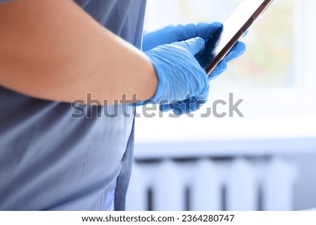 Closeup of doctor's hands in the latex gloves with a tablet pc

